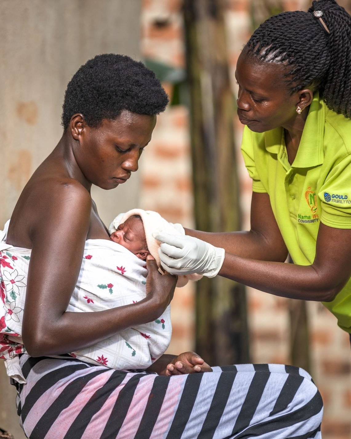A community health worker checks a newborn baby held by its mother during a home visit